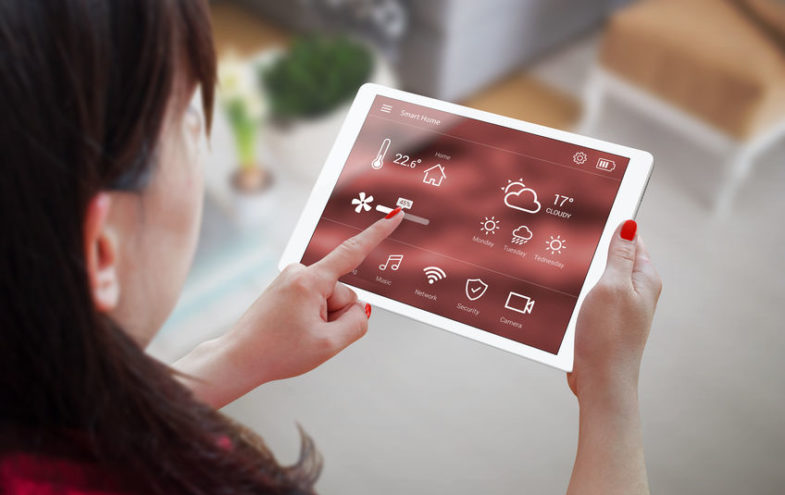Frau bedient Smart Home Anwendung auf einem Tablet.