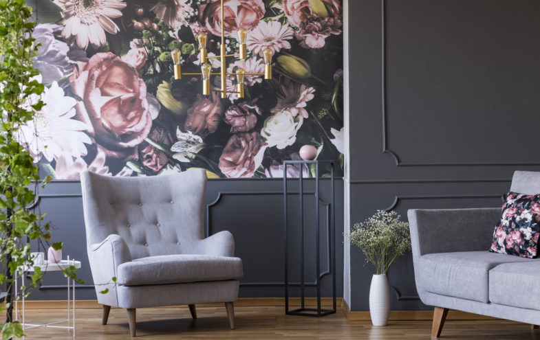 Sessel und Sofa vor einer Wand mit Blumenmuster.