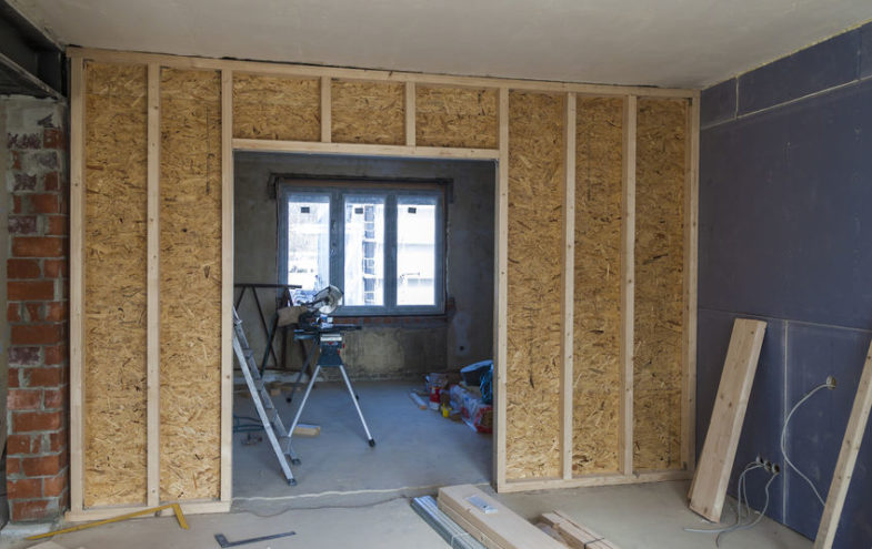 Trennwand aus Holzplanken und Spanplatten im Innenraum eines Wohnhauses.