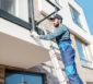 Handwerker auf einer Leiter überprüft das Geländer eines Balkons.