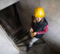 Bauarbeiterin auf einer Treppe zum auszubauenden Keller.