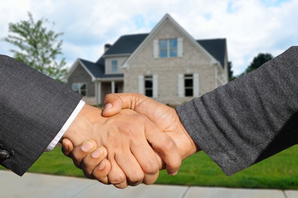 Zwei Männer schütteln sich die Hand vor einem Einfamilienhaus.