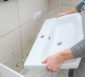 Handwerker hält ein neues Waschbecken zur Montage in den Händen.