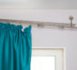 Schief hängende, abgerissene Vorhangschiene mit Vorhang.