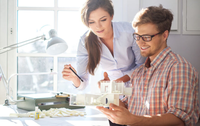 Architektin und Kunde im Büro betrachten ein 3D-Modell eines Neubaus.