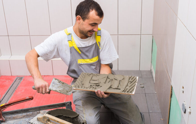 Handwerker mit Spachtel fliest das Bad.