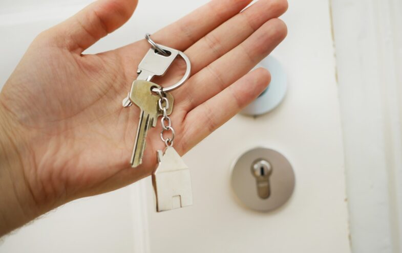 Eine Hand hält einen Schlüsselbund mit Haus-Anhänger.